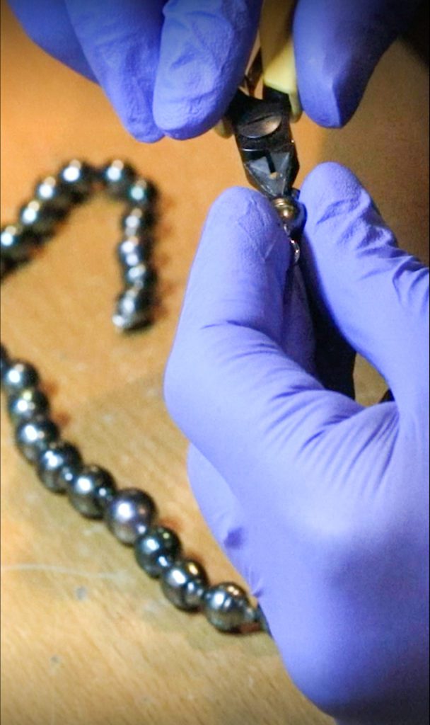 Image showcasing jeweler restringing pearls on a necklace