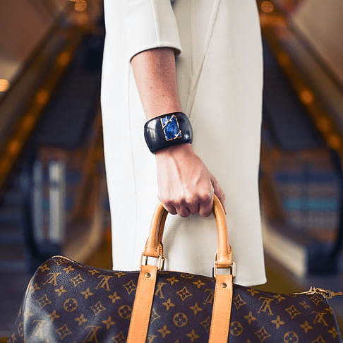 Image of woman wearing chunky bracelet holding Louis Vuitton bag