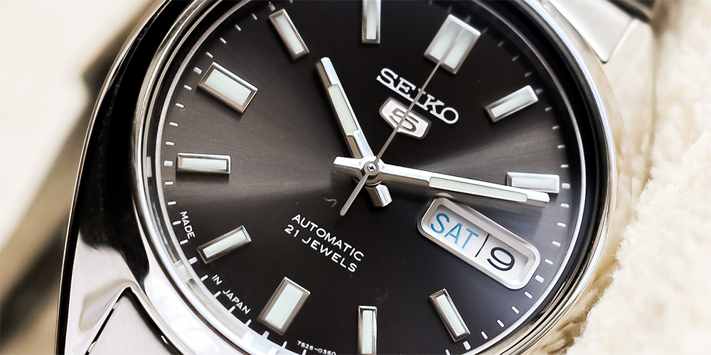 Close Up of Black Dial Seiko 5 Automatic 21 Jewels Watch Displayed on White Cloth